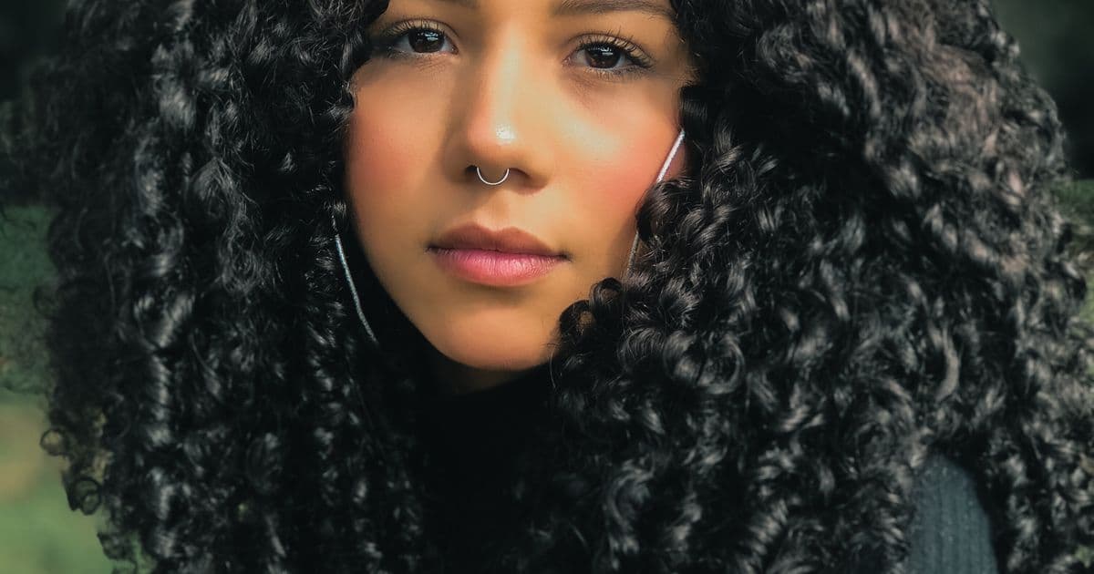 Femme aux cheveux crépus très texturés et volumineux, boucles définies encadrant le visage — innovation cosmétique et soin des cheveux texturés
